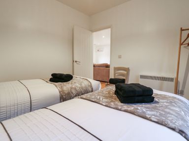 A bedroom with two single beds with folded towels on them a chair and a clothes rack at Hub House in Three Oaks near Hastings