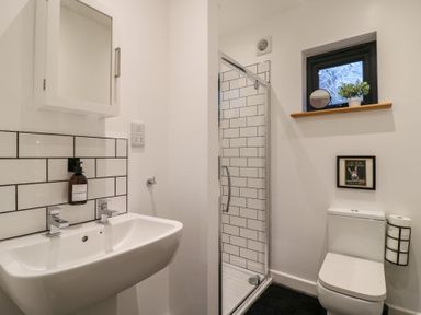 A bathroom with a sink mirror shower toilet and a small window at Hub House in Three Oaks near Hastings