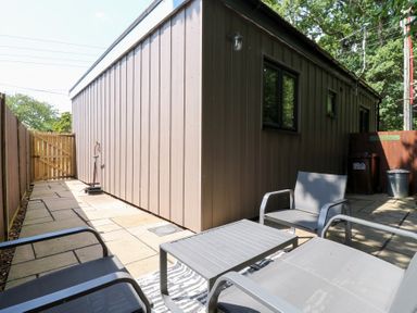 An outdoor area with chairs and a table beside a shed at Hub House Three Oaks near Hastings