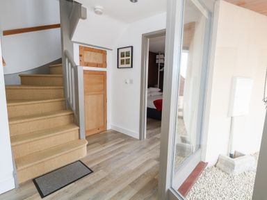 A hallway with a staircase and door to a bedroom at Coastguard Lookout in Wyke Regis