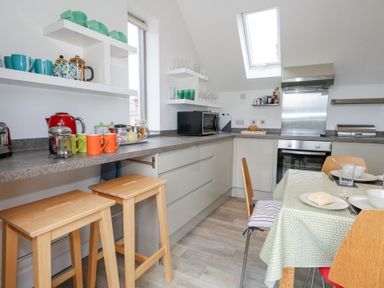 A kitchen with a counter, stools, and appliances at Coastguard Lookout in Wyke Regis