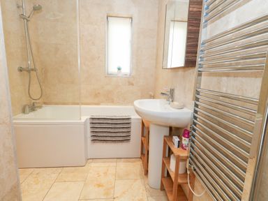 A bathroom with a bathtub, sink, and towel rack at Coastguard Lookout in Wyke Regis