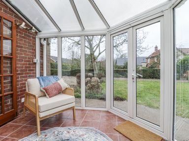 A conservatory with a chair and view of the garden at White Gates in Banham