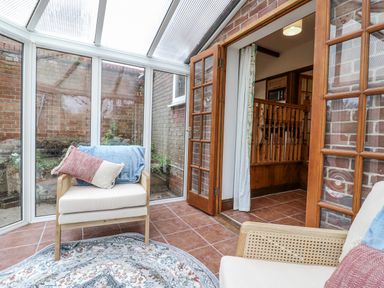 A conservatory with an armchair and rug at White Gates in Banham