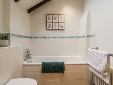 A bathroom with a bathtub and wall art at White Gates in Banham