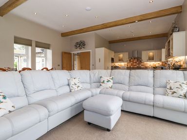 A living room with a sectional sofa and kitchen area at The Gatehouse 