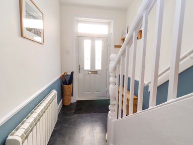 A hallway with a staircase and front door at Dinguardi in Seahouses