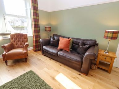 A living room with a sofa and chair at Dinguardi in Seahouses