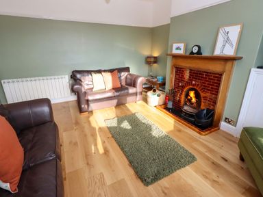 A living room with a fireplace and sofa at Dinguardi in Seahouses