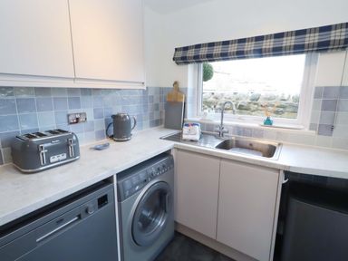 A kitchen with appliances and a window at Dinguardi in Seahouses