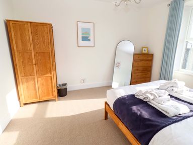 A bedroom with a bed, wardrobe, mirror, and dresser at Dinguardi in Seahouses