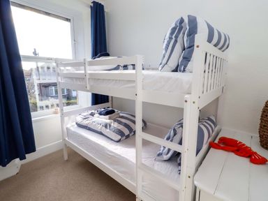 A bunk bed with striped pillows in a bedroom at Dinguardi in Seahouses
