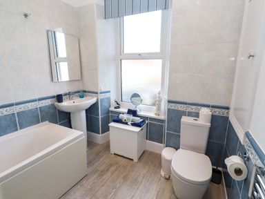 A bathroom with a bathtub, sink, and toilet at Dinguardi in Seahouses