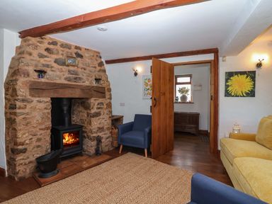 A living room with a fireplace and blue chairs at 1 Eastdon Cottages in Exeter