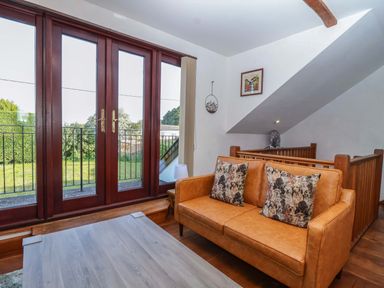 A living room with a sofa and double doors at 1 Eastdon Cottages Exeter