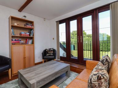 A living room with a bookshelf and coffee table at 1 Eastdon Cottages Exeter