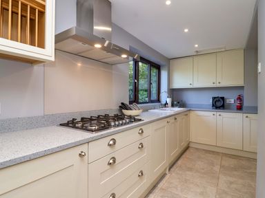 A kitchen with cabinets, stove, sink, and window at 1 Eastdon Cottages in Exeter