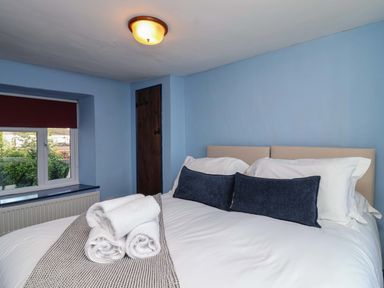 A bedroom with a bed and towels at 1 Eastdon Cottages in Exeter