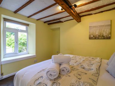 A bedroom with a bed and towels at 1 Eastdon Cottages in Exeter