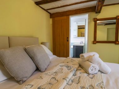 A bedroom with a bed and a door leading to a bathroom at 1 Eastdon Cottages Exeter