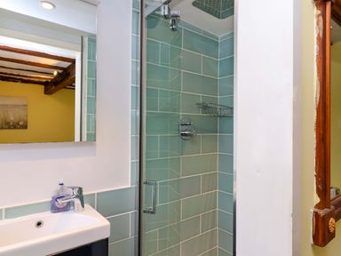 A bathroom with a shower, sink, and mirror at 1 Eastdon Cottages in Exeter