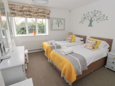 A bedroom with two single beds with yellow and grey blankets and pillows at The Smithy in Chathill near Seahouses