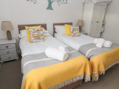 A bedroom with two single beds side by side with pillows blankets bedside tables and lamps at The Smithy in Chathill near Seahouses