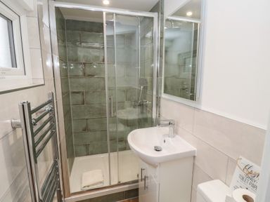 A bathroom with a shower enclosure sink and toilet at The Smithy in Chathill near Seahouses