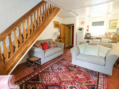 A living room with staircase and sofas at Riverbank Cottage in Beddgelert
