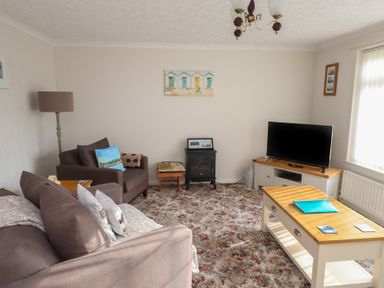 A living room with sofas a television on a stand a coffee table and a floor lamp at Samsons Place in Morfa Bychan