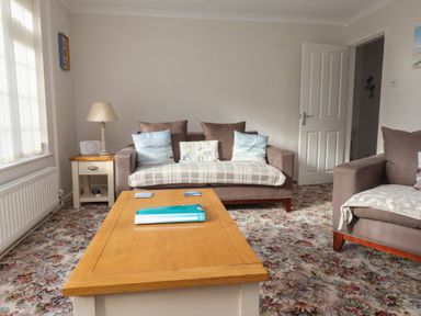 A living room with a sofa and armchair a wooden coffee table and a side table with a lamp at Samson's Place in Morfa Bychan