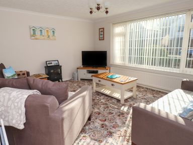 A living room with two sofas a coffee table a television and floral carpet at Samsons Place in Morfa Bychan