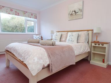 A bedroom with a bed pillows lamps and window at Samson's Place in Morfa Bychan