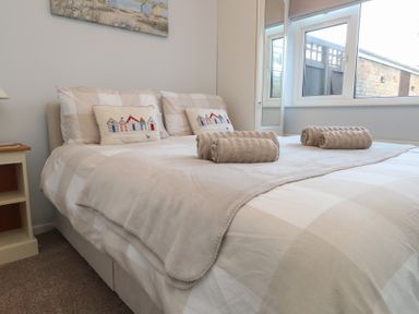 A bedroom with a double bed two rolled towels on bed and a window on the side at Samson's Place in Morfa Bychan