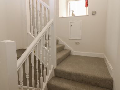 A staircase with a handrail and light switch at 21A High Street Jedburgh