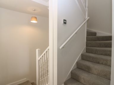 A staircase with carpet and a light fixture at 21A High Street in Jedburgh