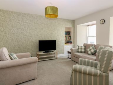 A living room with a television and bookshelf at 21A High Street, Jedburgh