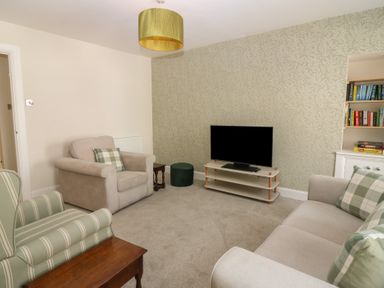 A living room with a television and seating at 21A High Street, Jedburgh
