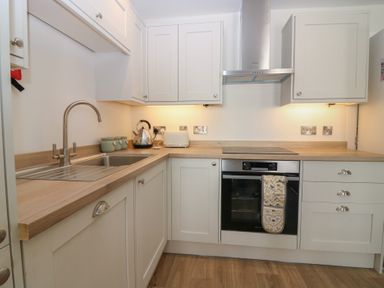 A kitchen with a sink, stove, and cabinets at 21A High Street, Jedburgh