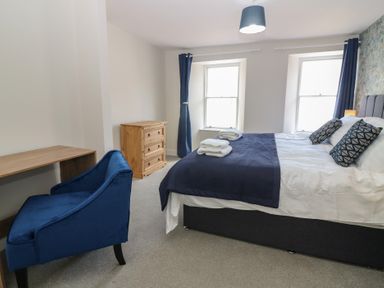 A bedroom with a bed, desk, chair, and dresser at 21A High Street in Jedburgh
