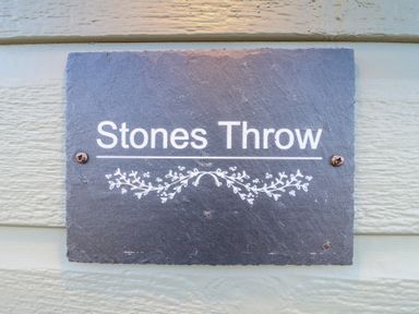 A stone sign with the text Stones Throw mounted on a light colored wooden wall at Stones Throw in Marston near Barkston