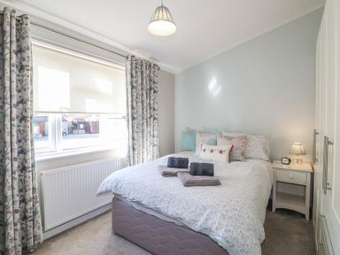 A bedroom with a double bed a bedside table and floral curtains at Stones Throw Marston near Barkston