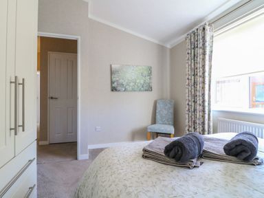 A bedroom with a bed folded towels on the bed a chair near a window and a wardrobe at Stones Throw in Marston near Barkston