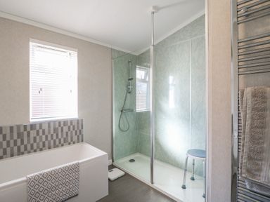A bathroom with a bathtub a shower enclosure with a stool and a towel rail at Stones Throw in Marston near Barkston