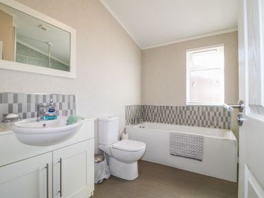 A bathroom with a sink vanity cabinet a toilet and a bathtub with a window at Stones Throw in Marston near Barkston