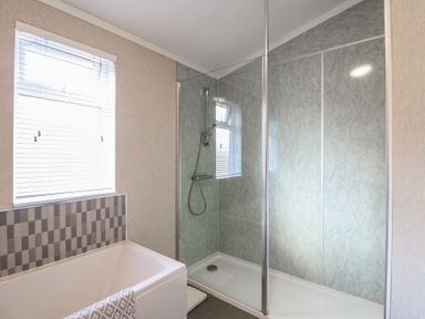 A bathroom with a bathtub under a window and a glass shower enclosure in a bathroom at Stones Throw in Marston near Barkston