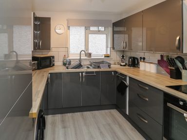 A kitchen with grey cabinets wooden countertops a window with a blind and various appliances at Lewis Lodge in St Ann's Chapel