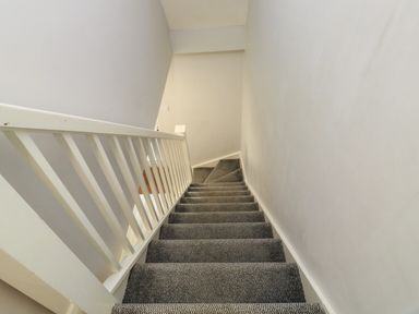 A staircase with gray carpet and white railing in a residential interior at Lewis Lodge in St Ann's Chapel