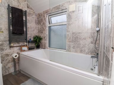A bathroom with a bathtub a shower a window and a towel rack at Hollycombe in Ilfracombe