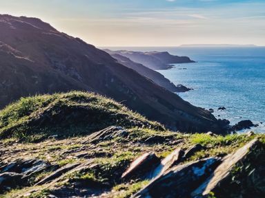 A coastal landscape with rocky cliffs and grassy areas by the ocean at Hollycombe in Ilfracombe